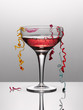 Confetti hanging from glass of pink champagne with lipstick stain