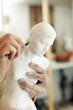 Hands of the sculptor with a statuette and a tool