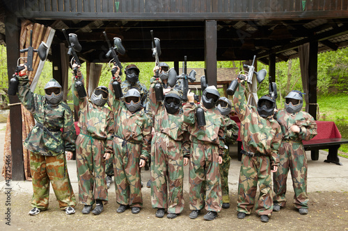 Photo: Boys dressed in camouflage stand in a row on a paintball base Boys dressed in camouflage stand in a row on a paintball base