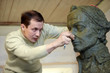 Sculptor works in the studio with plasticine model of bust