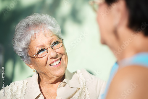 Photo: Old friends, two happy senior women talking in park Old friends, two happy senior women talking in park