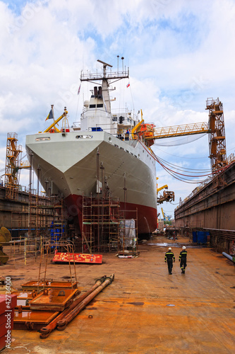 Photo: A large cargo ship is being renovated in shipyard. A large cargo ship is being renovated in shipyard.