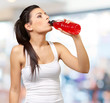 portrait of young sporty woman drinking isotonic drink indoor