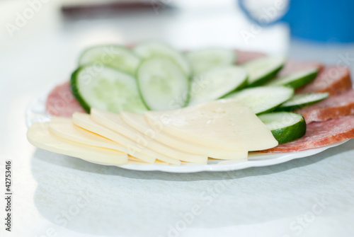 Photo: Dish with cut sausage, cheese and a cucumber Dish with cut sausage, cheese and a cucumber