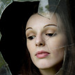 Visage de femme pensive derrière une vitre cassée.