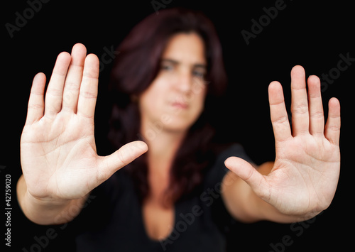 Photo: Woman with her two hands signaling to stop on a black background Woman with her two hands signaling to stop on a black background