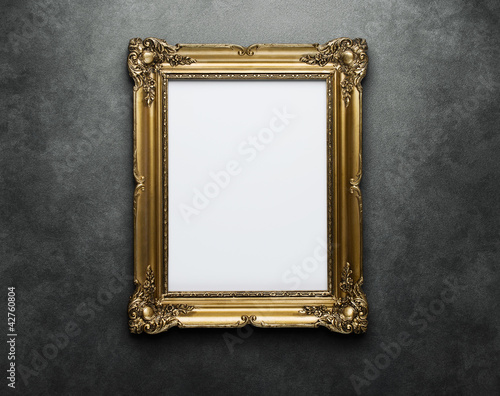 Photo: Ornate gold frame at the concrete wall with clipping path Ornate gold frame at the concrete wall with clipping path