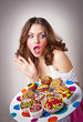 young surprised woman eating cakes isolated on white
