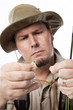 Fly fisherman threading line through hook.