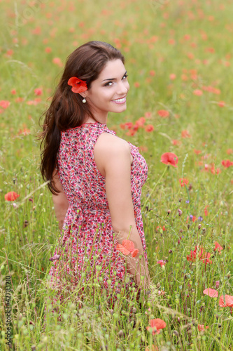Photo: Jeune femme en robe fleurie dans un champ de coquelicot Jeune femme en robe fleurie dans un champ de coquelicot
