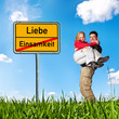 Foto: Ortsschild mit Paar auf Wiese Ortsschild mit Paar auf Wiese