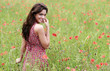 Jeune femme avec une robe fleurie dans un champ de coquelicot