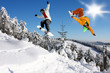 Snowboarders jumping against blue sky