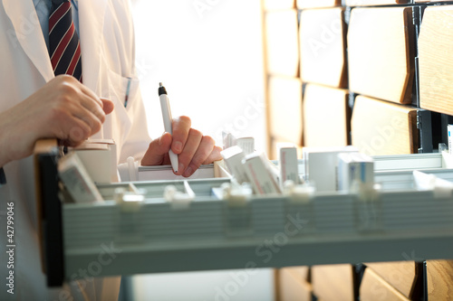 Photo: Pharmacist taking medicine from drawer. Pharmacist taking medicine from drawer.