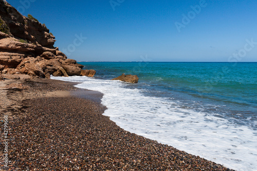Photo: Beautiful small pebble beach on the coast of Costa Dorado, Spain Beautiful small pebble beach on the coast of Costa Dorado, Spain
