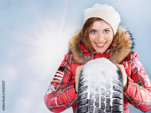 Foto: Beautiful woman with winter coat and snowy winter tyre Beautiful woman with winter coat and snowy winter tyre