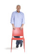 Señor de pie sujetando una silla roja.