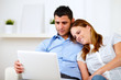Foto: Lovely couple smiling and reading on laptop Lovely couple smiling and reading on laptop