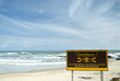 Caution sign on white sand beach