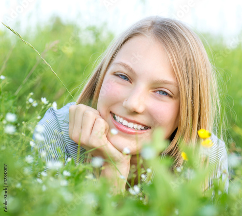 Photo: Smiling Girl Relaxing outdoors. Meadow Smiling Girl Relaxing outdoors. Meadow