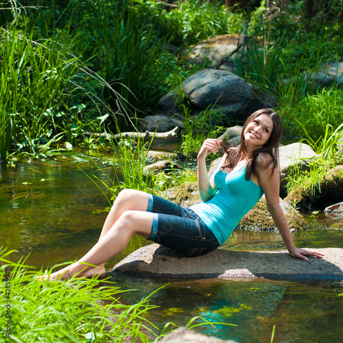 Photo: Young beautiful woman resting on river bank Young beautiful woman resting on river bank