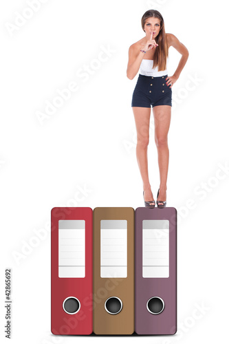 Photo: woman making silence sign on top of document files woman making silence sign on top of document files