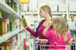 Mother and daughter shopping in oil section in supermarket