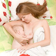 Mother is breast feeding baby in bed. Mother's love.