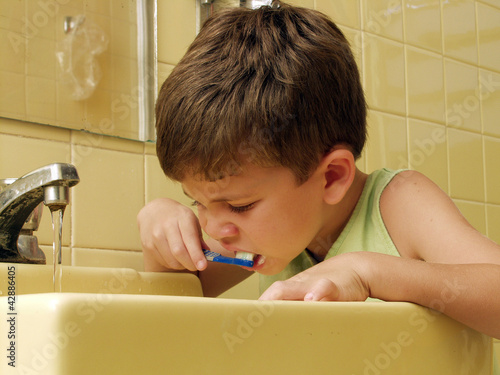 Foto: Niño cepillándose los dientes en un baño.lavando los dientes. Niño cepillándose los dientes en un baño.lavando los dientes.