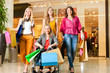 Vier Freundinnen beim Shoppen in einer Mall mit Rollstuhl