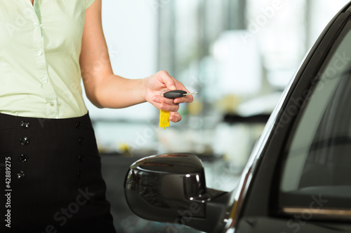 Photo: woman with car key opening new or rental auto woman with car key opening new or rental auto