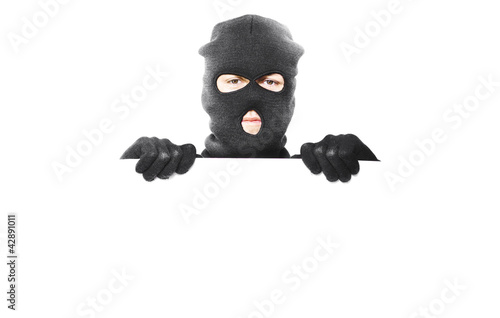 Photo: Thief with robbery mask holding blank white board Thief with robbery mask holding blank white board