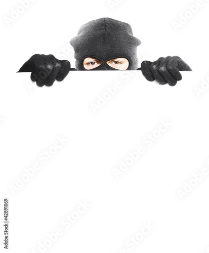 Photo: Isolated robber hiding behind a empty white sign Isolated robber hiding behind a empty white sign
