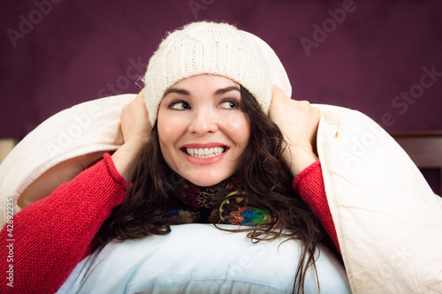 Photo: Happy woman peeking out from under blankets Happy woman peeking out from under blankets
