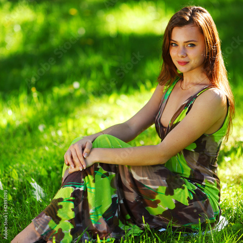 Photo: brunette sitting on green grass brunette sitting on green grass
