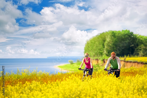 Photo: happy couple cycling in canola fields happy couple cycling in canola fields
