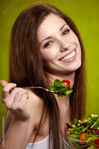 Foto: The beautiful cheerful young woman has breakfast salad The beautiful cheerful young woman has breakfast salad