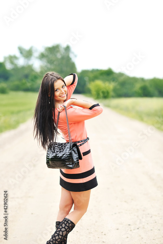 Photo: Beautiful young girl with handbag posing near a copyspace Beautiful young girl with handbag posing near a copyspace