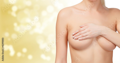 Photo: Female controlling breast for cancer, gold blured background Female controlling breast for cancer, gold blured background