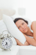 Close-up of an alarm clock with a woman who just wakes up