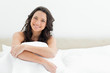 Smiling attractive brunette sitting in her bed