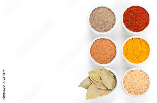 Photo: Different spices in white bowls isolated on white background. Different spices in white bowls isolated on white background.