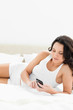 Close-up of an attractive woman texting on her bed