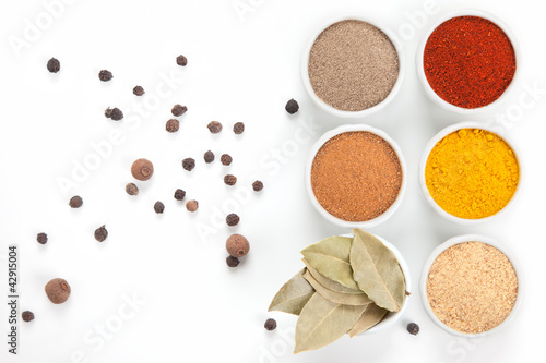 Photo: Different spices in white bowls isolated on white background. Different spices in white bowls isolated on white background.