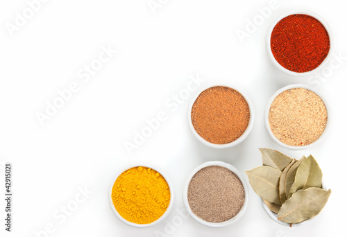 Photo: Different spices in white bowls isolated on white background. Different spices in white bowls isolated on white background.