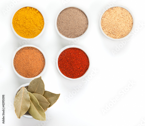 Photo: Different spices in white bowls isolated on white background. Different spices in white bowls isolated on white background.