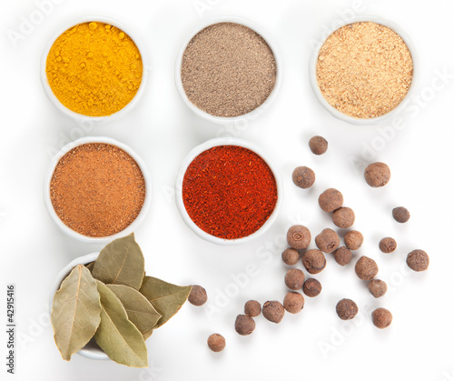 Photo: Different spices in white bowls isolated on white background. Different spices in white bowls isolated on white background.