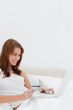 Redheaded using her credit card online while sitting on her bed