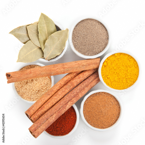 Photo: Different spices in white bowls isolated on white background. Different spices in white bowls isolated on white background.