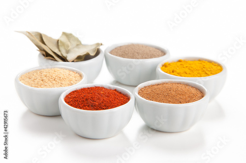 Photo: Different spices in white bowls isolated on white background. Different spices in white bowls isolated on white background.